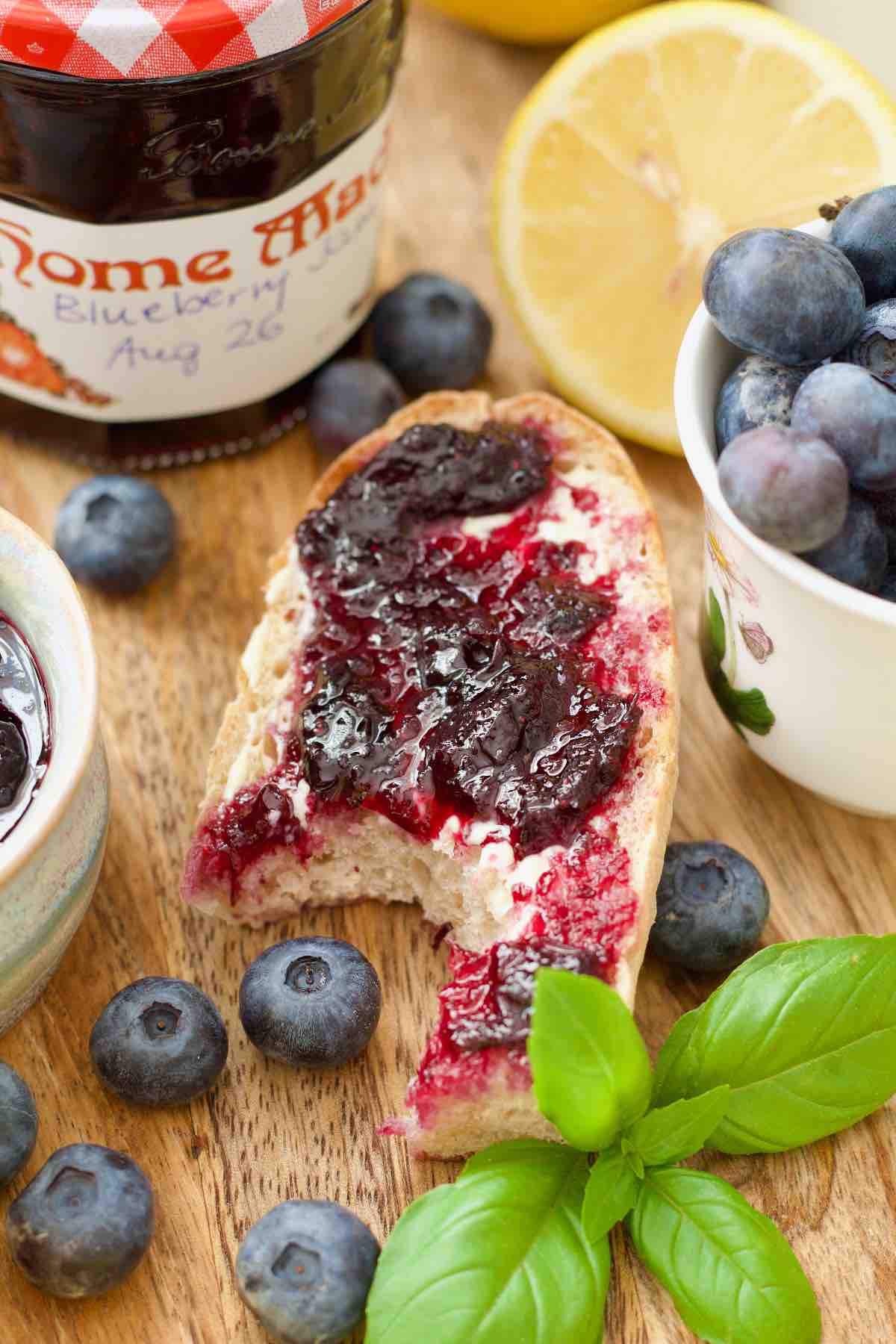 Small piece of baguette topped with blueberry jam with bite taken out of it.