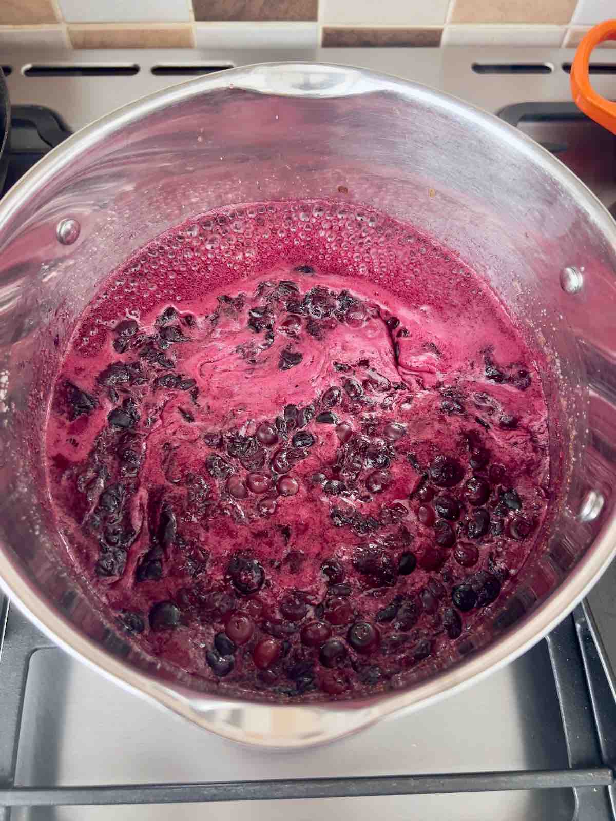 Blueberry jam rapidly boiling in a pan.