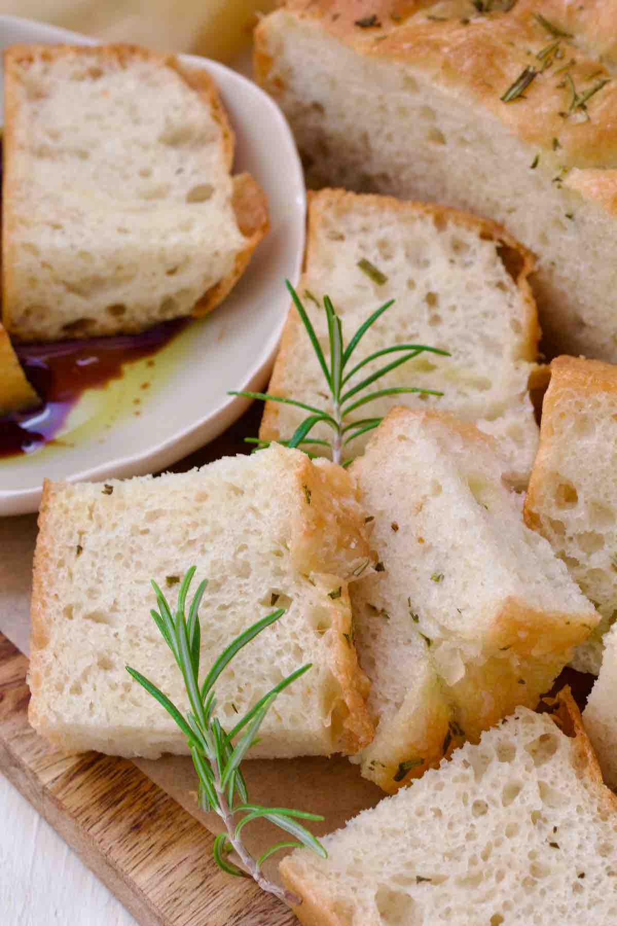 Focaccia pieces piled up on the board, garnished with fresh rosemary.