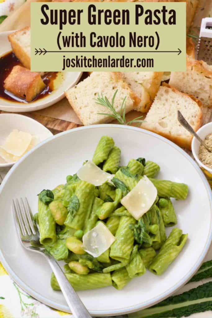 Bowl of green pasta with parmesan shavings and focaccia slices.