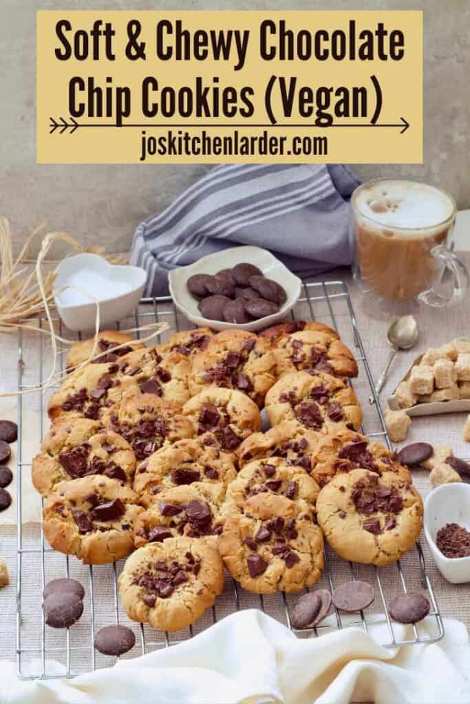 Baked chocolate chip cookies on cooling rack with coffee, and chocolate buttons.