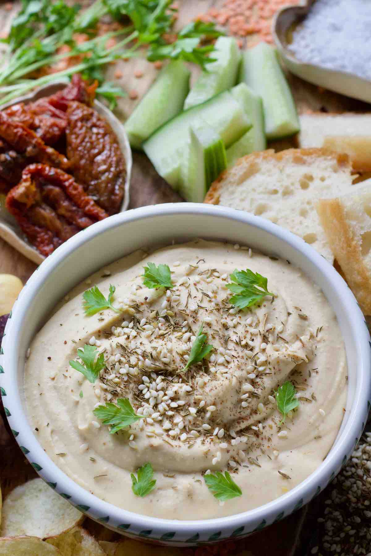 Close up of red lentil hummus sprinkled with seeds and decorated with parsley.