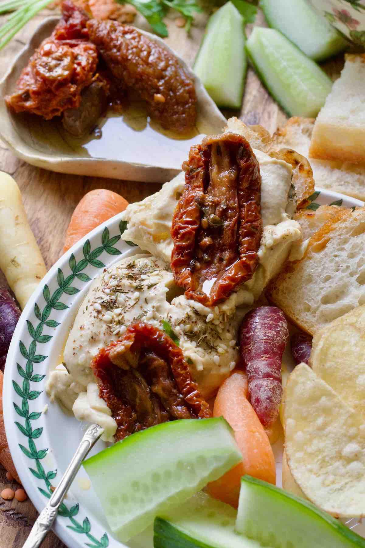 Close up of hummus on a piece of focaccia with sun dried tomato on top.