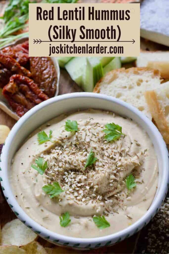 Close up of red lentil hummus sprinkled with seeds and decorated with parsley.